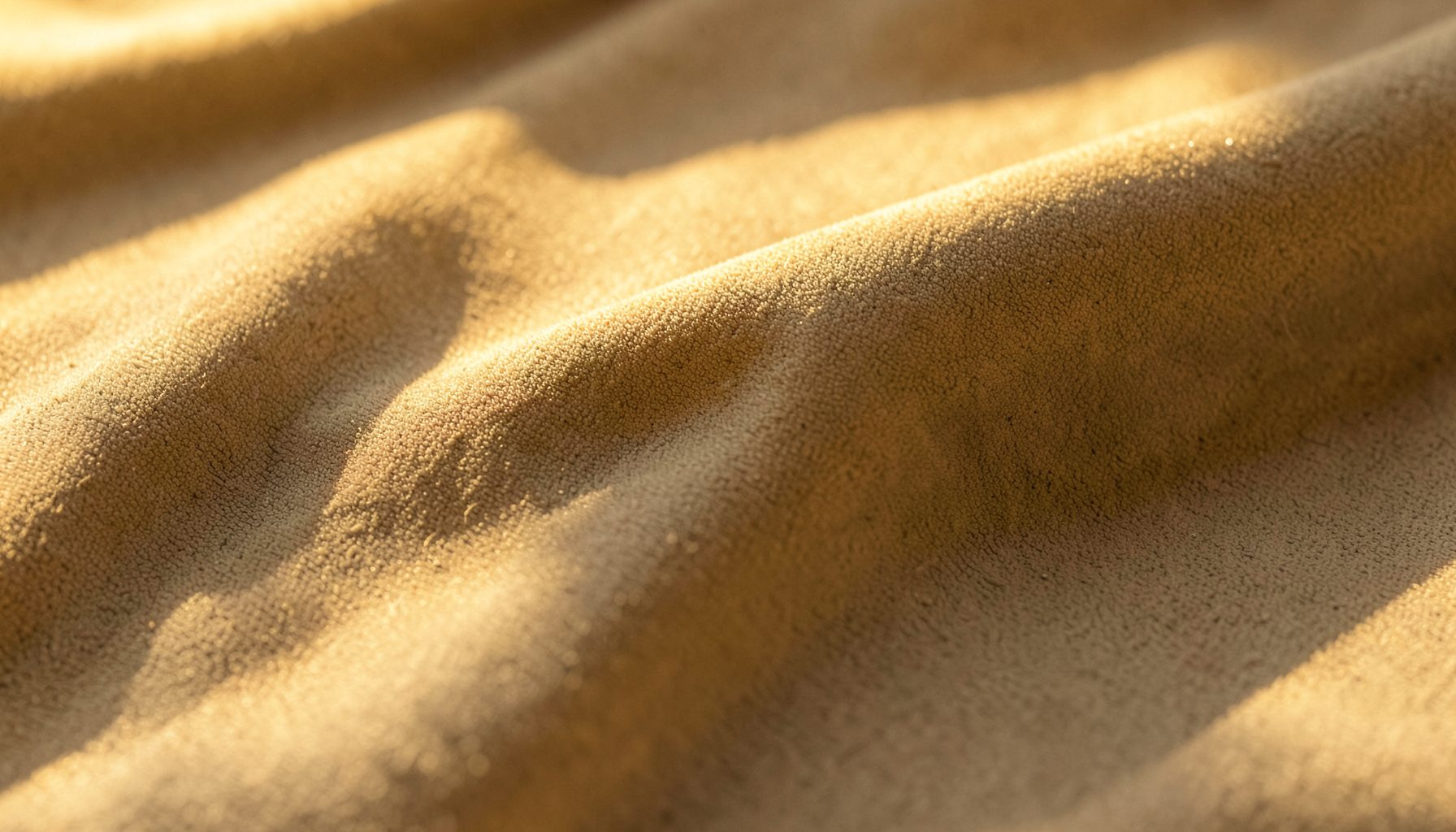 Roll of fireproof decorative fabric in warm neutral tones, photographed in golden-hour light with soft shadows across the textile surface.