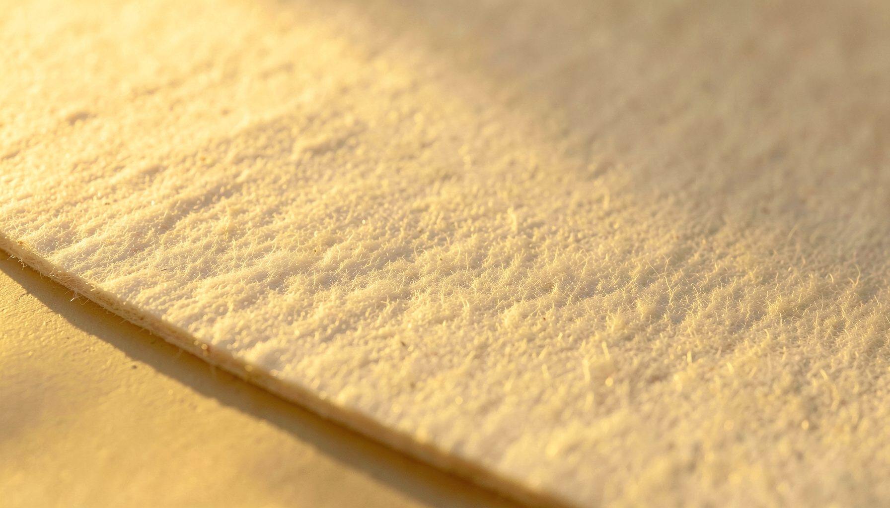 Polypropylene felt sheet with fine fiber mat surface, pale white-cream color, soft directional light